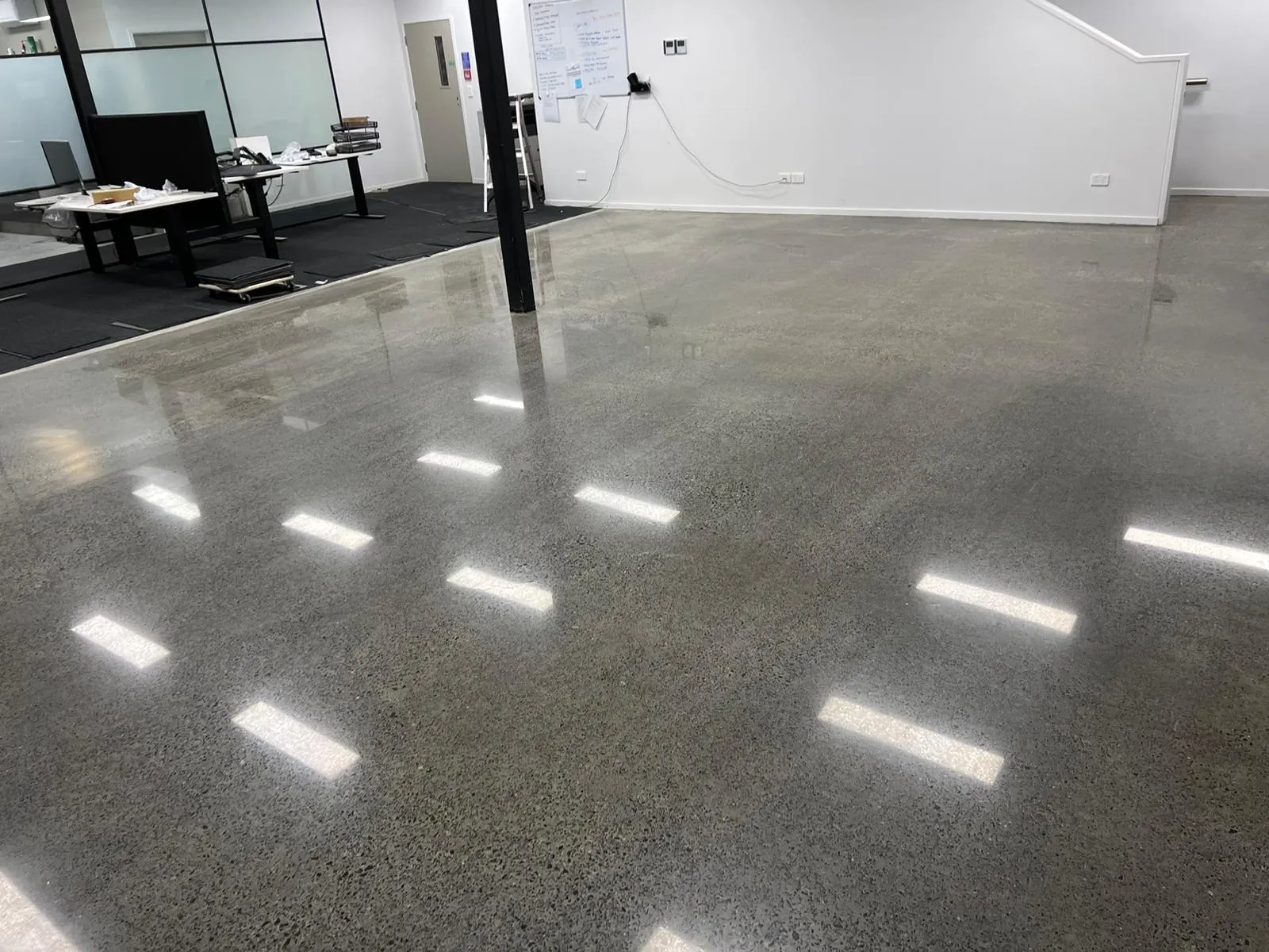 Polished concrete floor by Apollo Flooring in an Auckland office, ceiling lights reflected in the finish